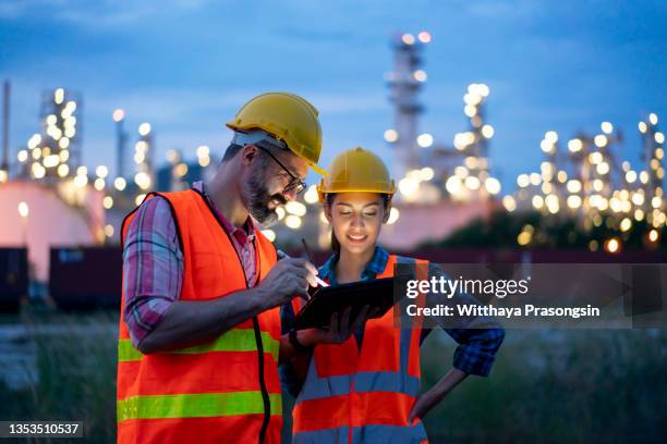 engineer using tablet near oil refinery at night. - gas engineer stockfoto's en -beelden