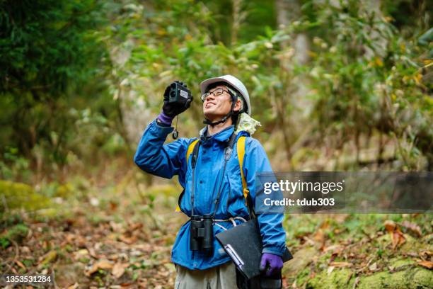 mid adult researcher or environmentalist with data gathering equipment in the forest - climate scientist stock pictures, royalty-free photos & images