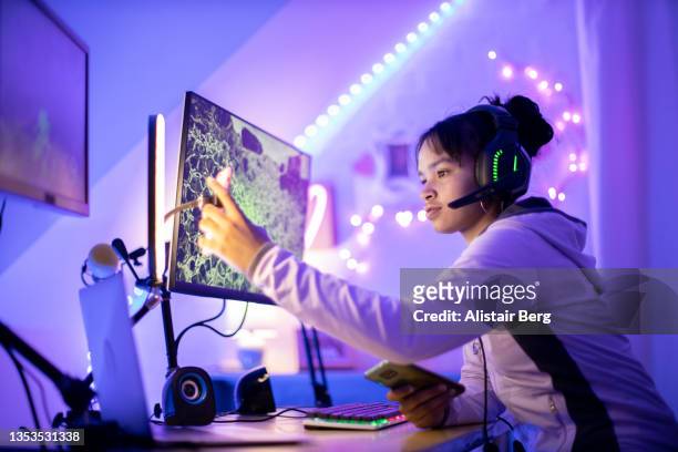 teenage female gamer using her smart phone at night - playing computer games stock-fotos und bilder