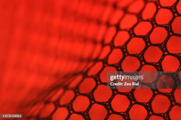 black netting material against red background in full frame - tulle netting stock-fotos und bilder