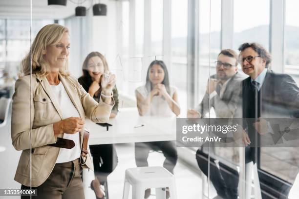 experienced business woman writting on a glass wall - brightly lit stock pictures, royalty-free photos & images