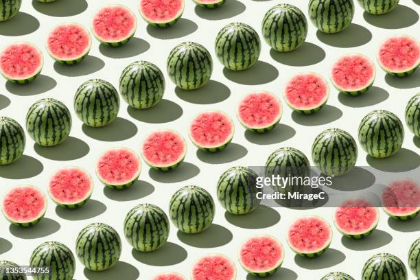 halved watermelons and whole watermelons repetition on green - half fotografías e imágenes de stock