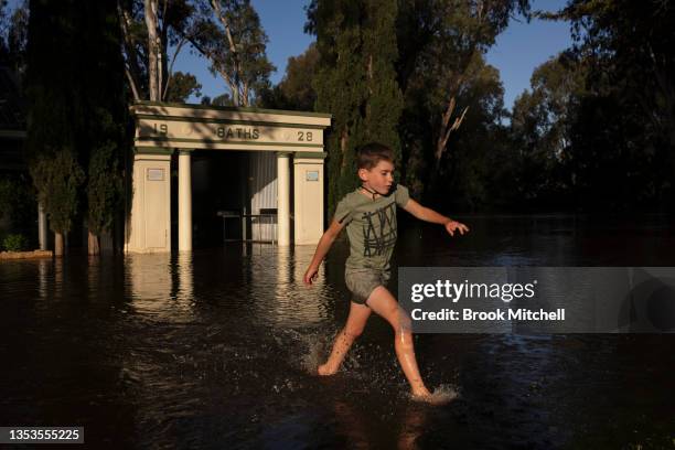 Benedict plays in ankle deep water as the Lachlan River starts to spill over on November 16, 2021 in Forbes, Australia. Residents in Forbes and...