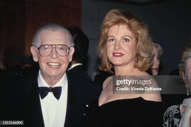 American comedian and actor Milton Berle , wearing a tuxedo and bow tie, with his wife, America fashion designer Lorna Adams, wearing a black outfit...