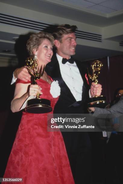 American actress Erika Slezak, wearing a red evening gown with a white flower, and American actor Peter Bergman, wearing a tuxedo and bow tie, attend...