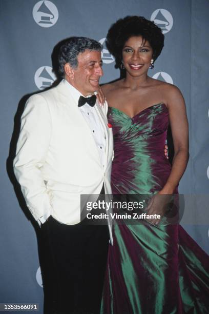 American singer Tony Bennett, wearing a white tuxedo and black bow tie, and American singer, songwriter, and actress Natalie Cole , wearing a green...