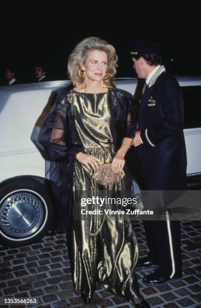 American actress Candice Bergen, wearing a gold evening dress with a sheer black shawl, arriving for the 49th Golden Globe Awards, held at the...