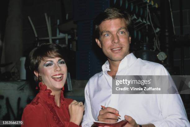 American actress Colleen Zenk, wearing a red high-neck outfit, and American actor Peter Bergman, wearing a white shirt which is open at the collar,...