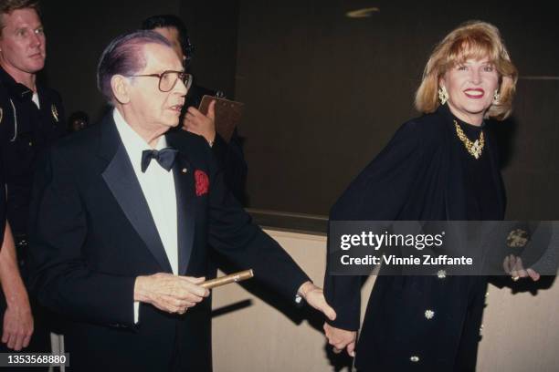 American comedian and actor Milton Berle , wearing a tuxedo and bow tie, with his wife, America fashion designer Lorna Adams, wearing a black coat...