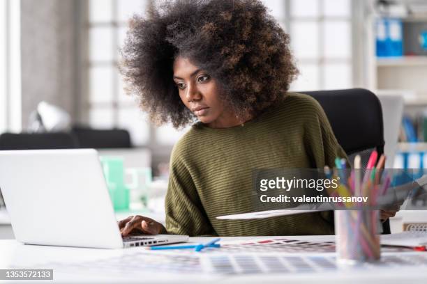 confident african-american  female designer in a creative office, working on laptop - graphic design studio stock pictures, royalty-free photos & images