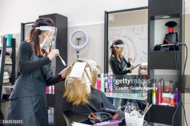 frau mit highlights im friseursalon von einem friseur mit visier - highlights stock-fotos und bilder