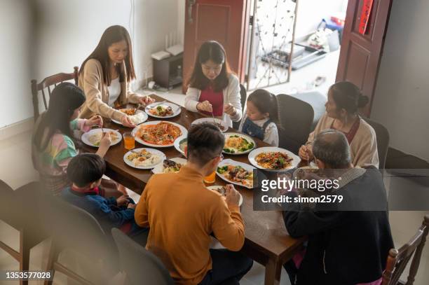 three generations of joyful asian family celebrating and enjoying reunion dinner at home during chinese new year - 65 year old asian women stockfoto's en -beelden
