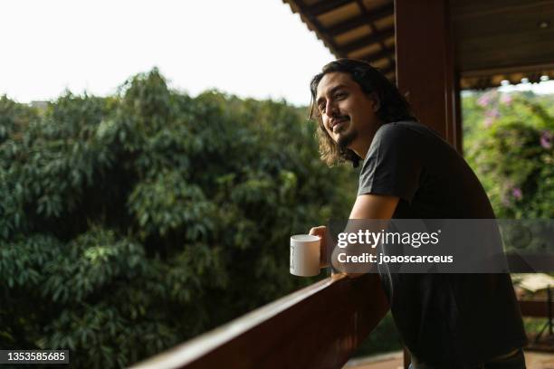 man drinking coffee or tea on porch amid nature - royalty free space images stockfoto's en -beelden