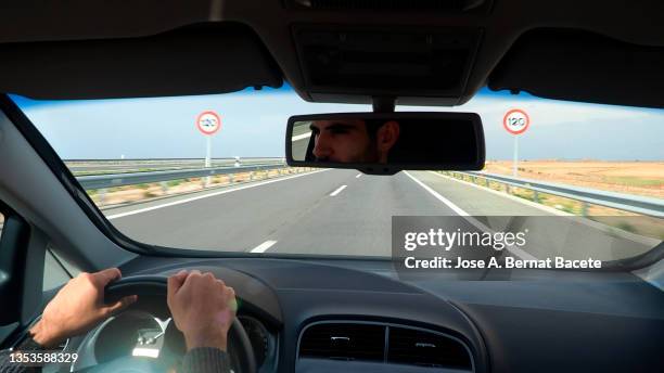 car point of view, young man driving a car on a two-lane highway. - car dashboard windscreen stock pictures, royalty-free photos & images