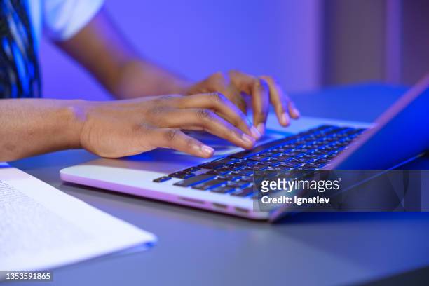 female hands, typing an email on a laptop in a purple illumination - redactie stockfoto's en -beelden