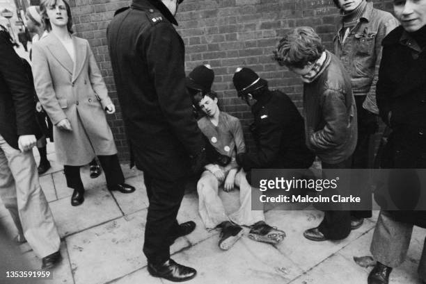 Policemen check on a young man sitting on the pavement following unrests during a protest against the National Front, far-right fascist political...