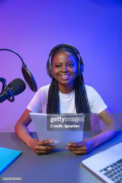 a a smiling dark skinned podcaster with braids on a violet background - radio broadcasting stock pictures, royalty-free photos & images