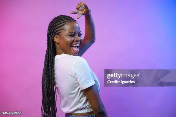 a young dark-skinned happy blogger dances on camera with a smile on a purple background - photo shoot set up stock pictures, royalty-free photos & images