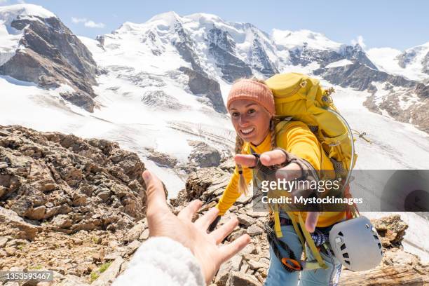 kletterer hilft teamkollegen mit helfende hand - mountains pov stock-fotos und bilder