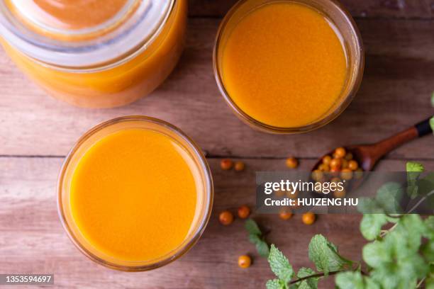 two glasses of fresh sea buckthorn juice on a wooden table, top view - buckthorn stock pictures, royalty-free photos & images