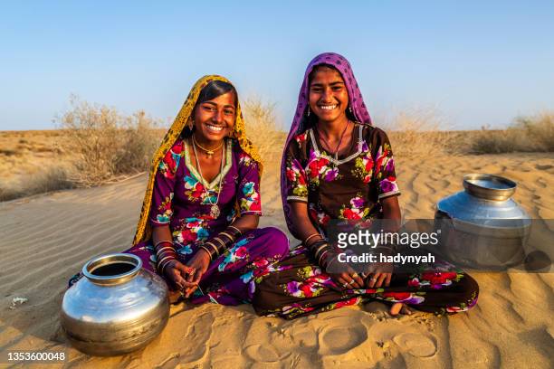 giovani ragazze indiane che trasportano acqua dal pozzo, villaggio del deserto, india - rajasthan foto e immagini stock