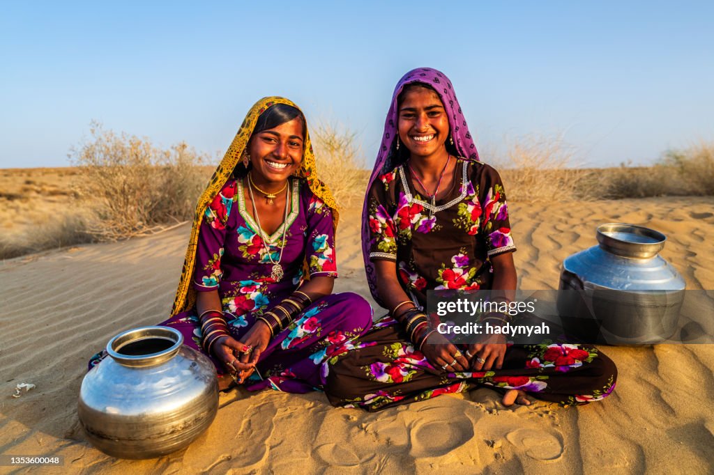 Young Indian girls carrying water from well, desert village, India