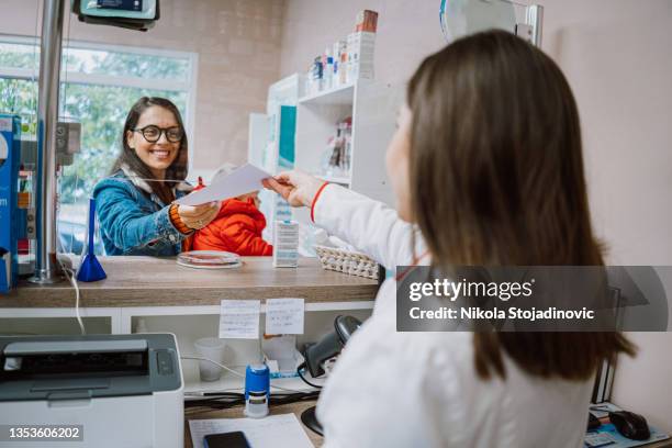 the pharmacist gives the mother with baby medicine - paying doctor stock pictures, royalty-free photos & images