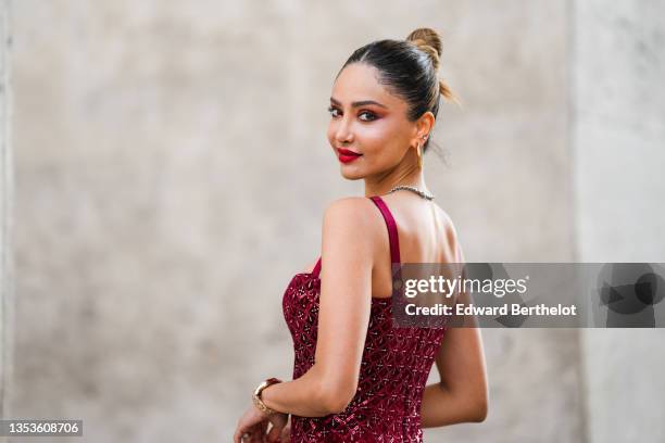 Patricia Gloria Contreras wears gold earrings from Louis Vuitton, a gold chain necklace, a silver and rhinestones necklace, a burgundy velvet with...