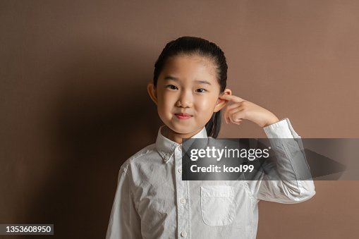 Little Girl Plug Ears with Fingers on Brown Background Little Girl Plug Ears with Fingers on Brown Background