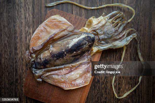 dried squid on dark wood table - fish in bulb stock pictures, royalty-free photos & images