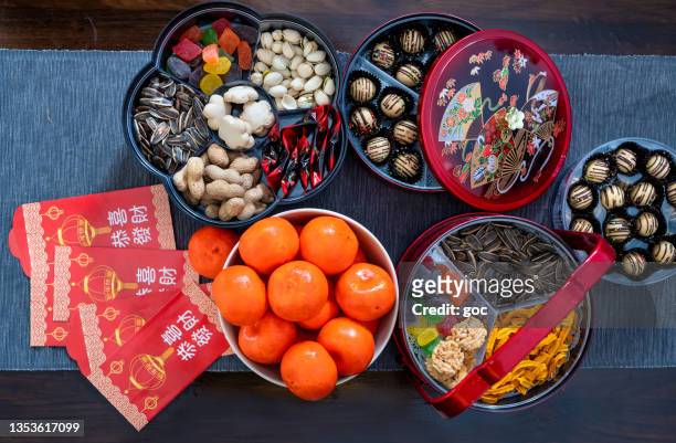 traditionelle chinesische snacks, rote päckchen (ang pow) und orangen für das chinesische neujahrsfest auf dem holztisch - chinese new year home stock-fotos und bilder