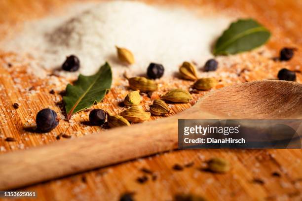 close up of pickling salt and spices such as caraway, cardamom, juniper berry, bay leaves and a wooden kitchen spoon. - cardamom stock pictures, royalty-free photos & images