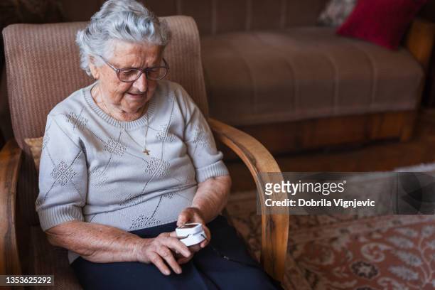 großmutter sitzt zu hause und benutzt blutdruck - puls oxymeter stock-fotos und bilder