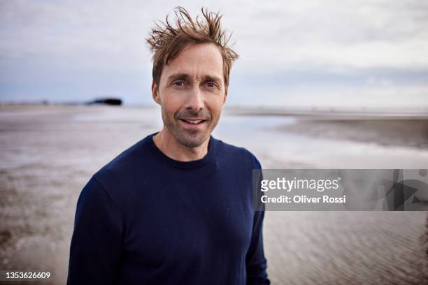 portrait of man with tousled hair on the beach - tousled hair man stock pictures, royalty-free photos & images