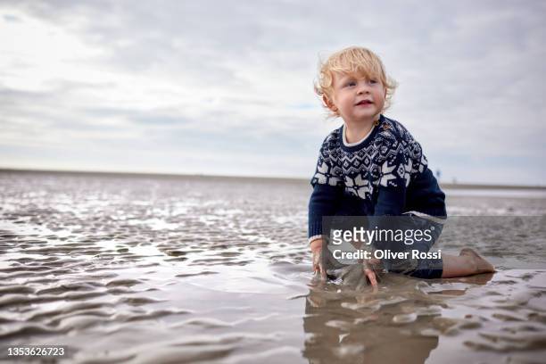 cute boy on the beach at low tide - barefoot boy fotografías e imágenes de stock