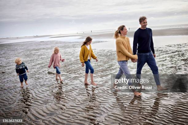 family walking together on the beach at low tide - barefoot girl stock pictures, royalty-free photos & images