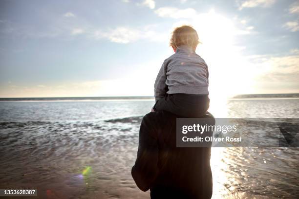father carrying son on shoulders on the beach - 肩車 ストックフォトと画像