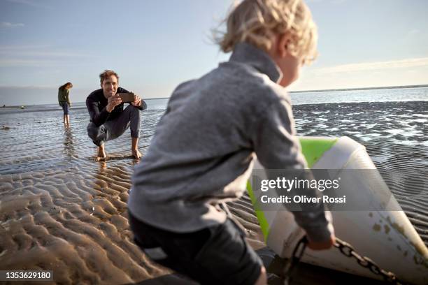 father taking smartphone picture of his son with buoy at the beach - sea iphone stock pictures, royalty-free photos & images