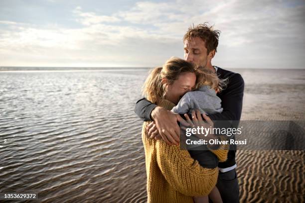 affectionate family hugging on the beach - vater mutter kind stock-fotos und bilder