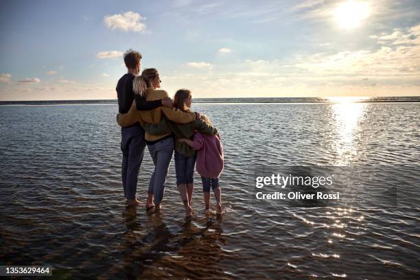 family watching sunset in the sea - familia de dos generaciones fotografías e imágenes de stock