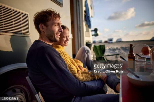 couple relaxing at camper van at sunset - wochenendaktivität stock-fotos und bilder