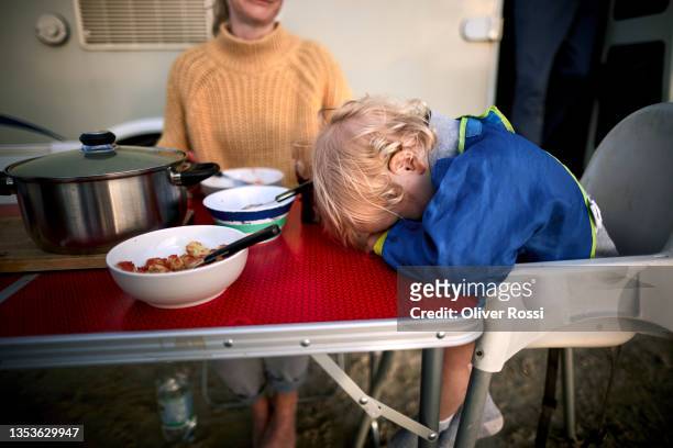 tired boy resting his head on camping table - head on table stock-fotos und bilder