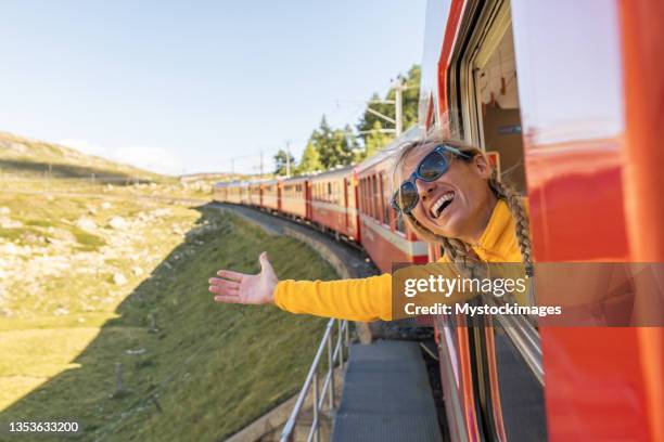 fröhliche frau, die eine zugfahrt in der schweiz genießt, die arme ausgestreckt - schweizerische kultur stock-fotos und bilder
