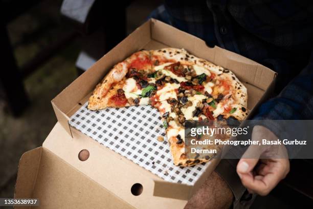 close up of a man eating pizza in a public park - takeaway box stock pictures, royalty-free photos & images