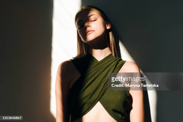beautiful girl in the sunlight with a shadow on the background of a white wall. - fashion dress stock-fotos und bilder