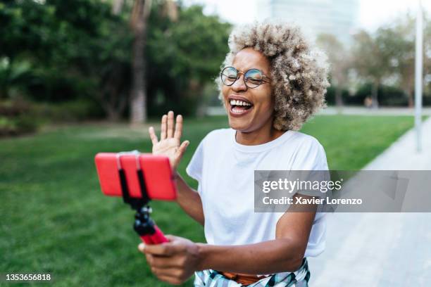 african-american vlogger recording content for her social networks with a mobile phone in city park. - man talking at the phone outdoor stock-fotos und bilder