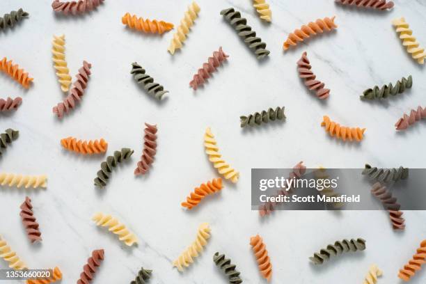 colored pasta scattered on white marble - dry pasta stock pictures, royalty-free photos & images