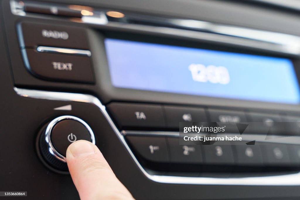 Driver pressing a button to turn on the music or radio in the car.