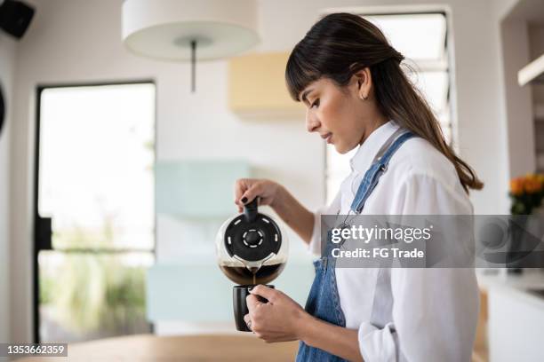 young woman pouring coffee at home - caffeine molecule stock pictures, royalty-free photos & images