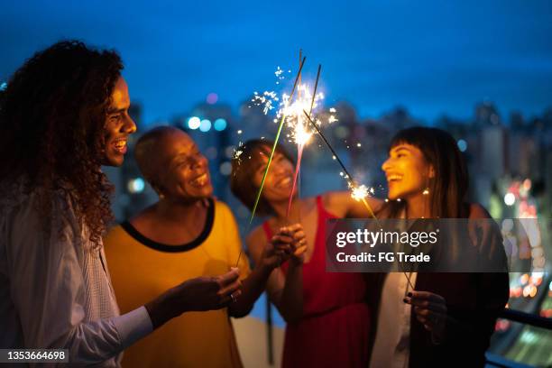 freunde feiern silvester mit wunderkerzen zu hause - wiedersehenstreffen stock-fotos und bilder